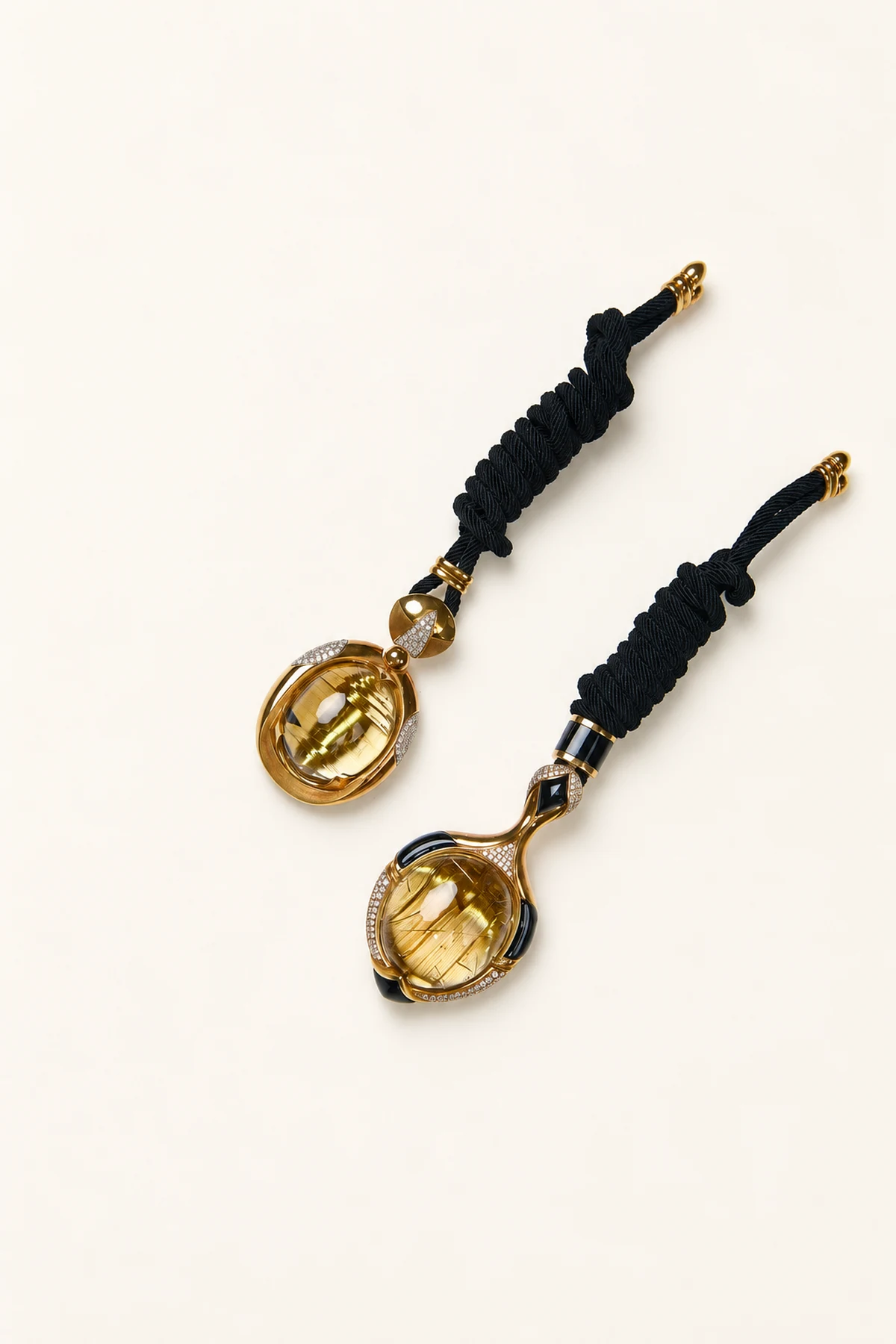 Two hand-carved rutilated crystal pendants with dark braided cords