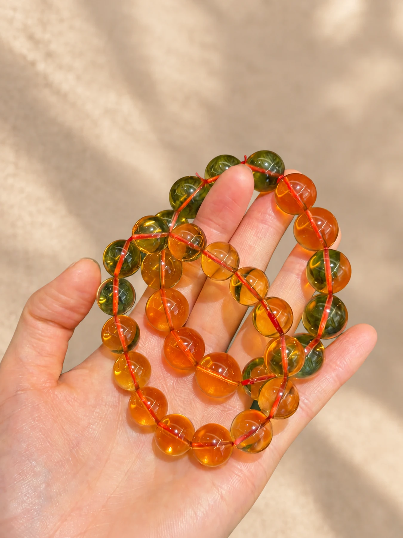 Several orange and green-toned natural-stone strands held in a hand