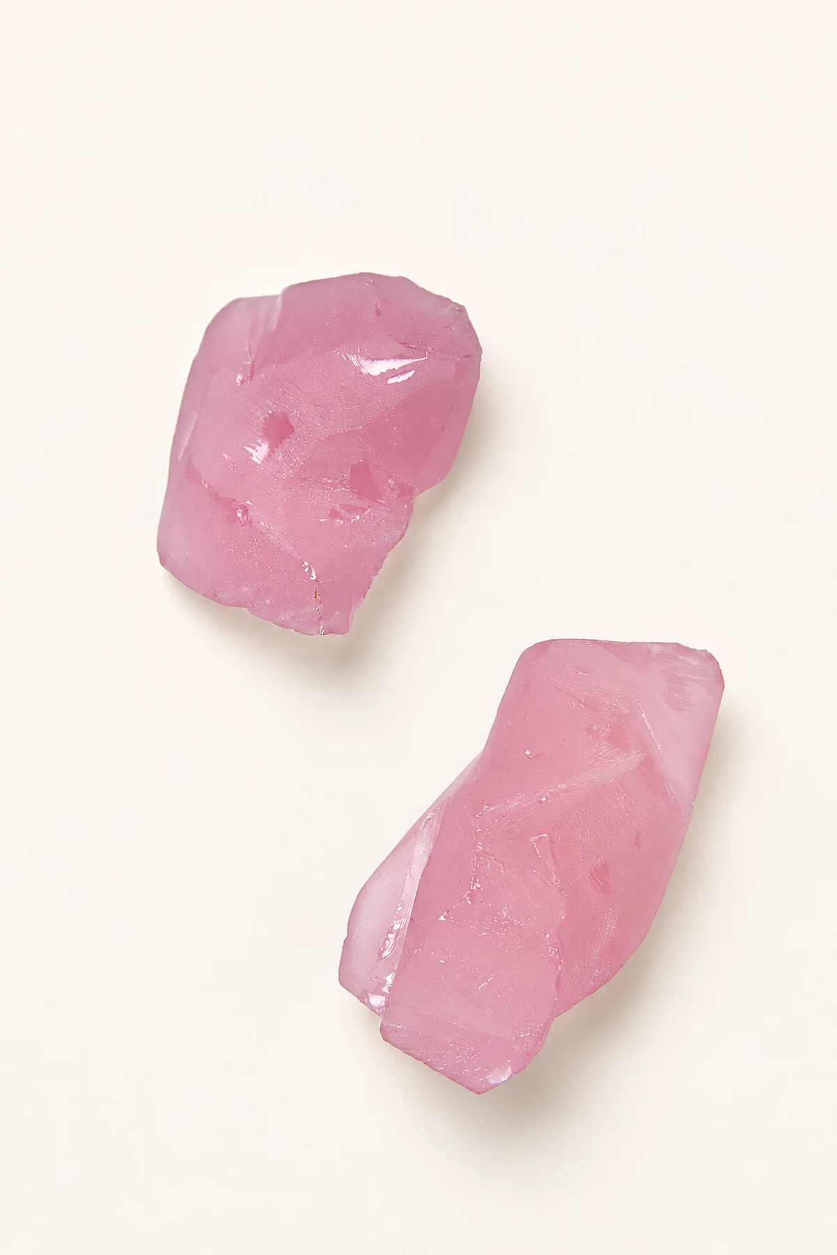 Two pieces of pale pink rough stone on a pale surface