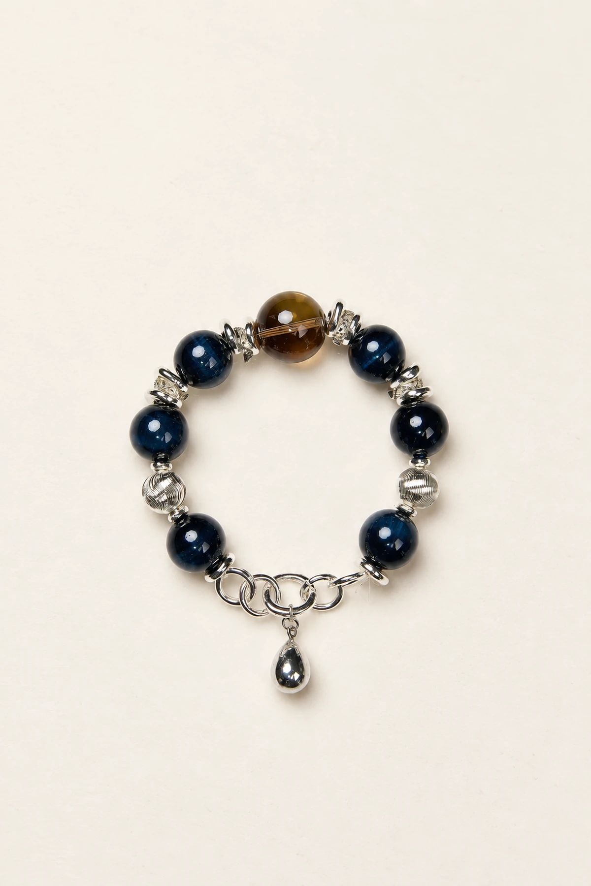 Blue-toned bracelet with a brown bead, silver spacers and a metallic charm