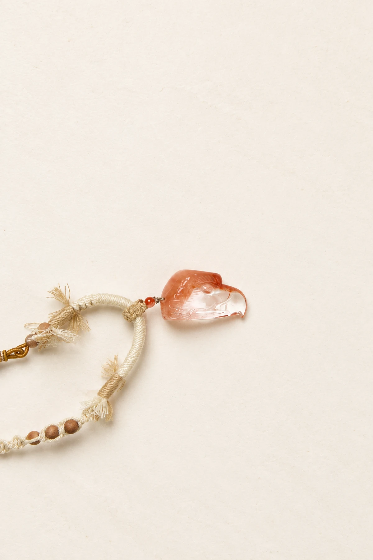 Carved eagle-head pendant in warm red and clear crystal on a braided cord