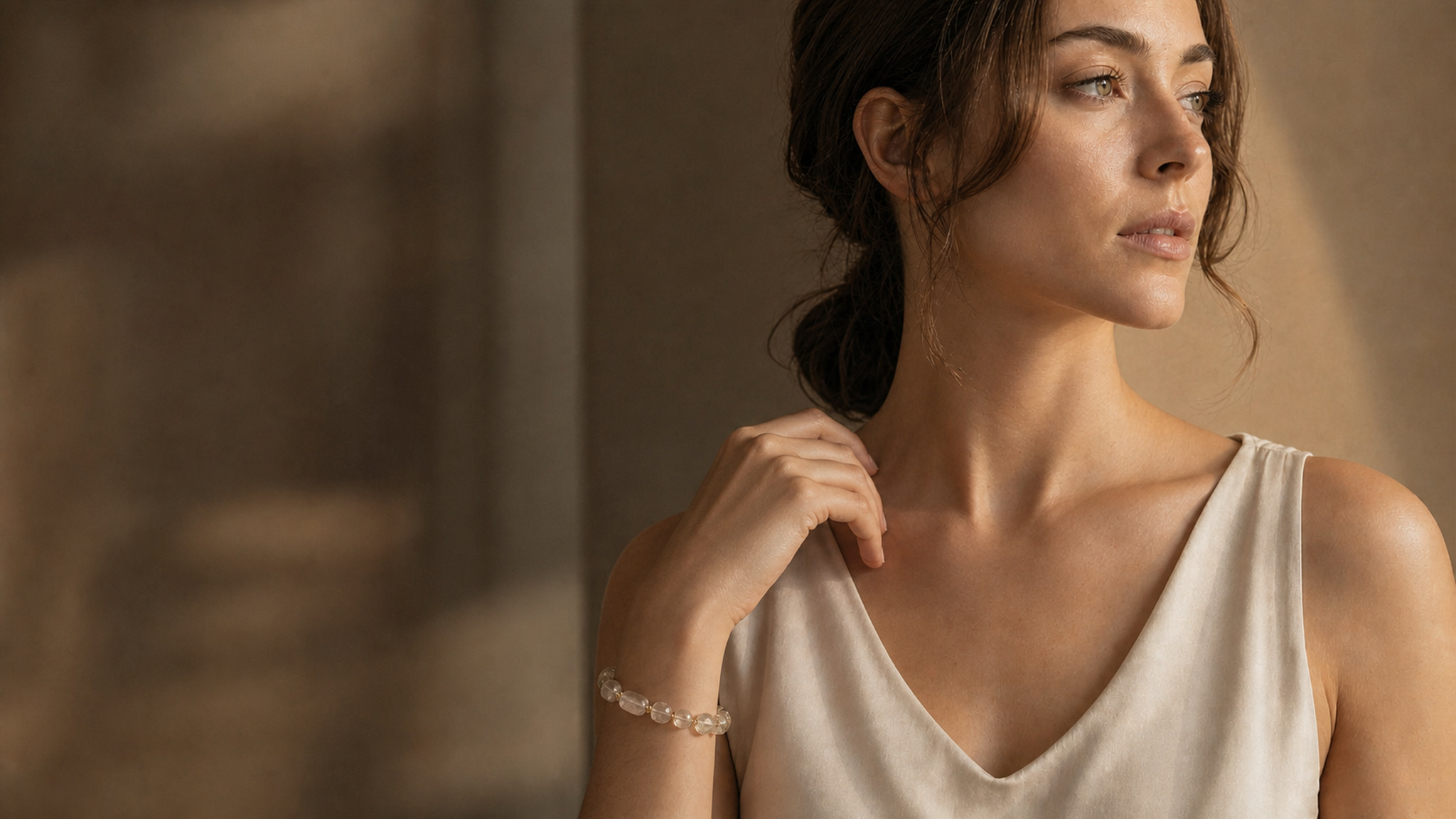 Young European woman wearing a clear natural-crystal bracelet in warm mineral light